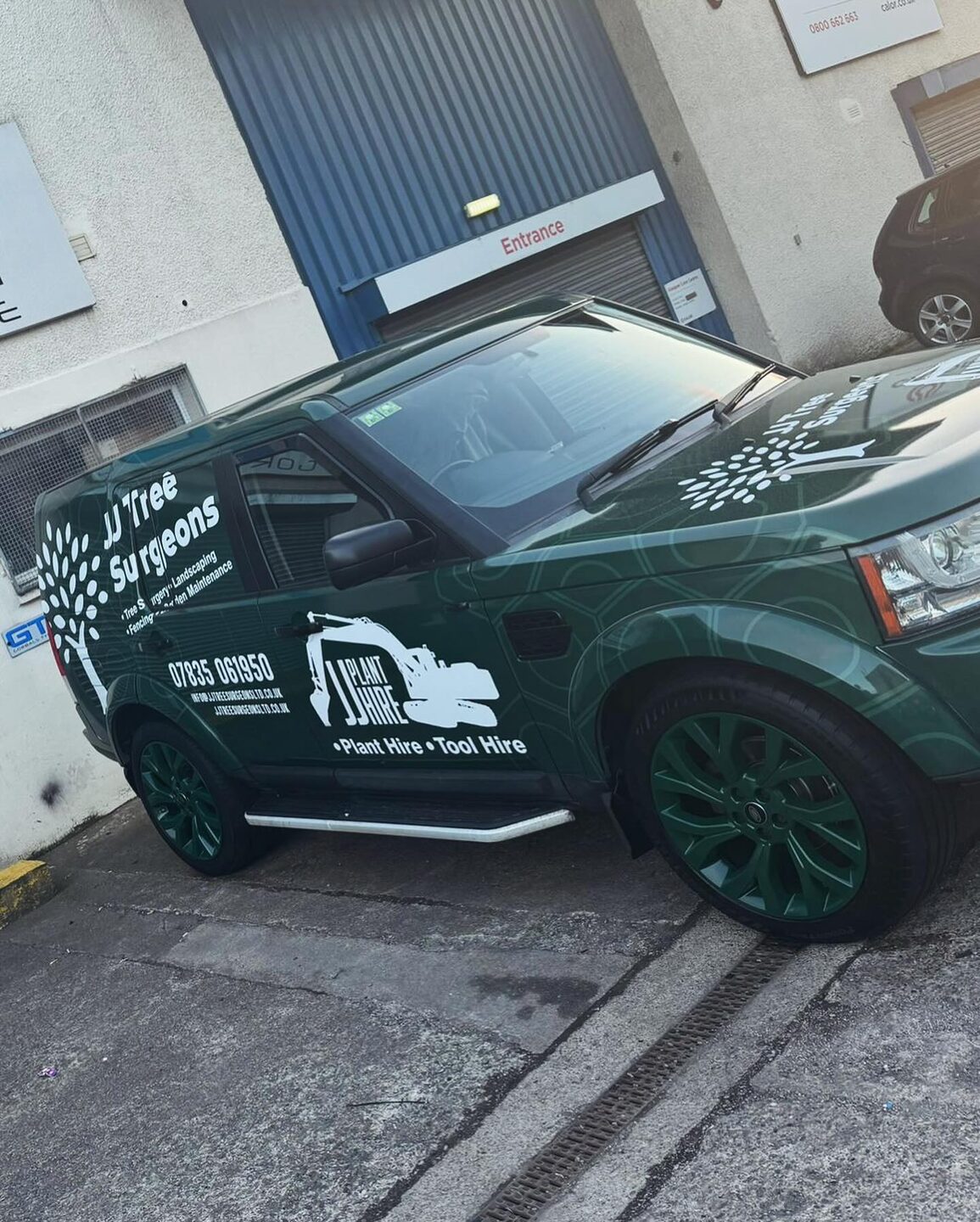 The JJ Tree Surgeons dark green vehicle with the tree mark and phone number on the door