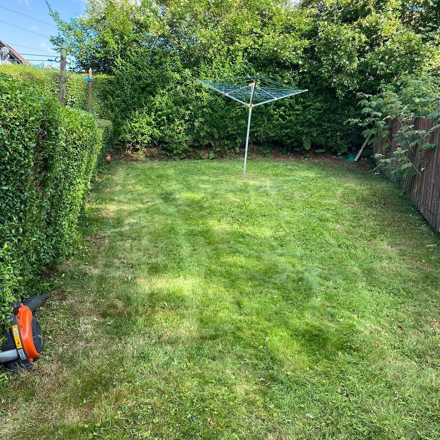 A back garden freshly mown with clean edges and the drying pole standing clear