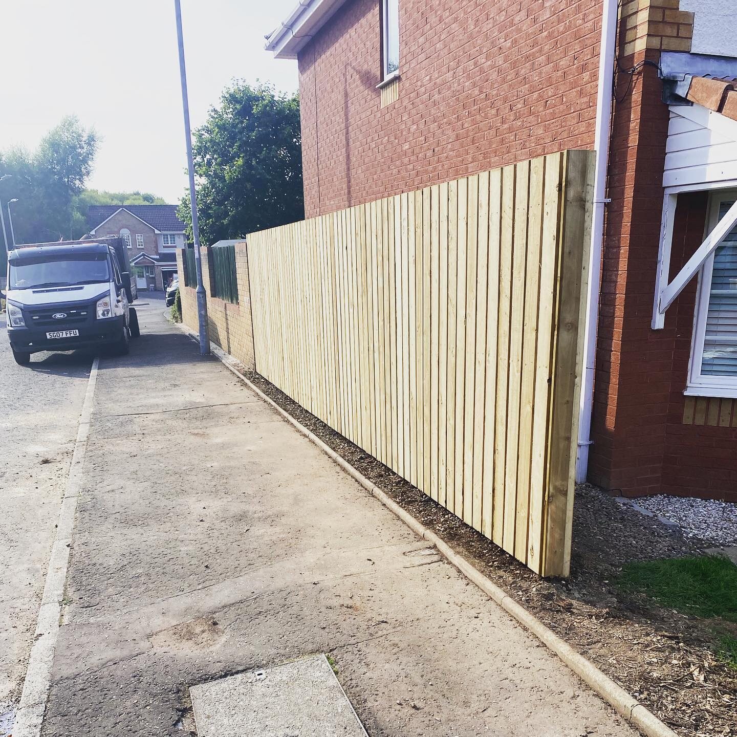 A new six foot double-boarded timber fence running along a boundary beside a house