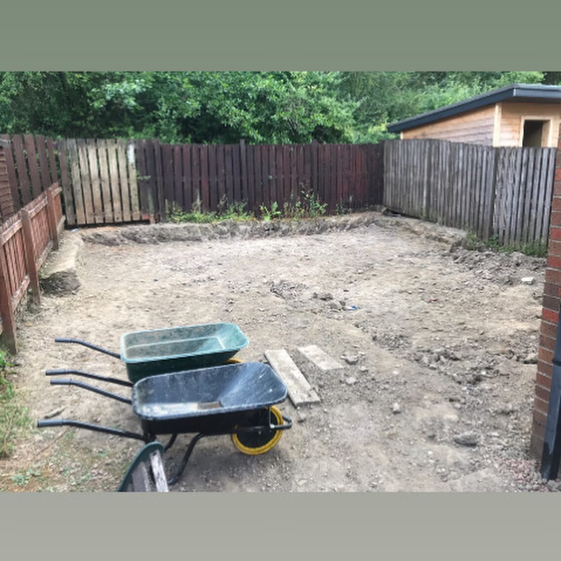 A back garden dug out to bare soil with a wheelbarrow standing in it