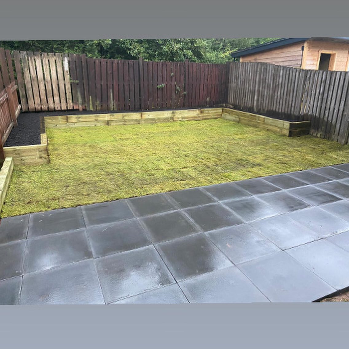 A finished garden at dusk with new turf, slabs and a fence