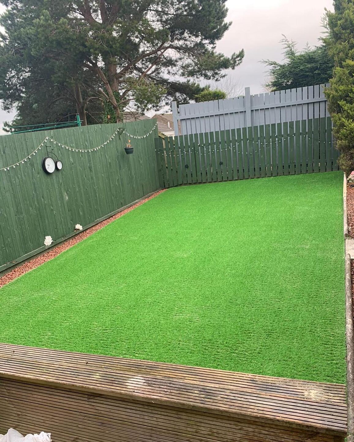 A small back garden finished in bright artificial grass with a brick border