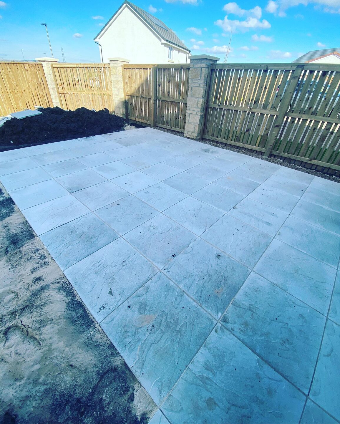 A large slabbed patio freshly laid across the back of a new-build house